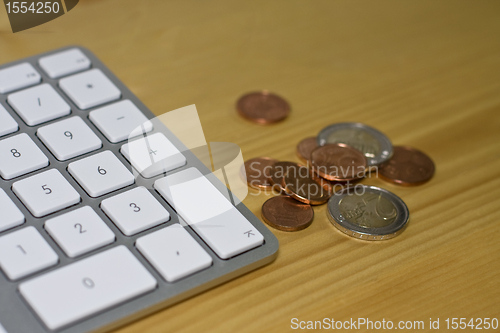 Image of Keyboard and euro coins on wooden desk