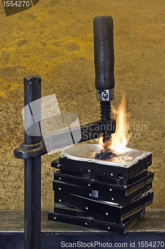 Image of burning stack of hard drive pressed together with clamp