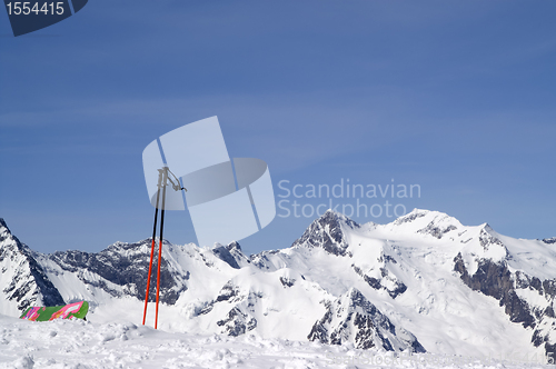 Image of Ski poles and snowboard against snowy mountains