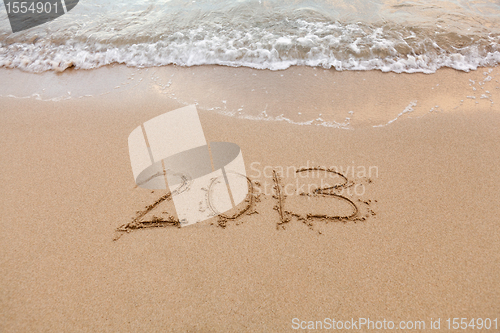 Image of 2013 written in sand with waves