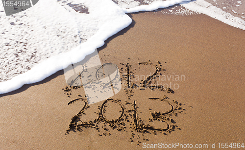 Image of 2012 and 2013 written in sand with waves