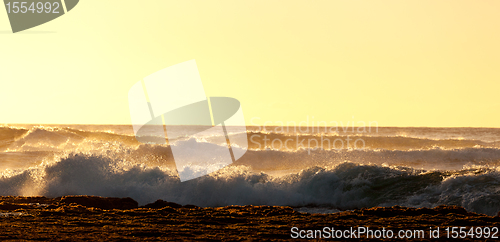 Image of Setting sun lights crashing waves