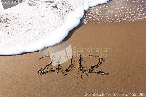 Image of 2012 written in sand with waves