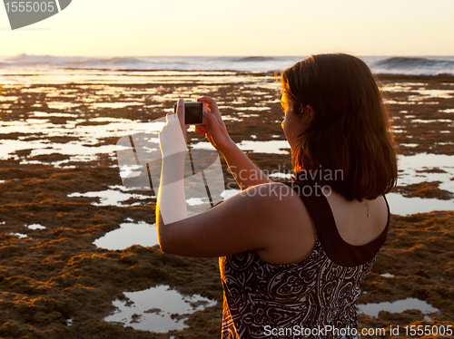 Image of Girl taking photo of sunset on phone