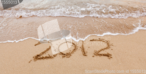 Image of 2012 written in sand with waves