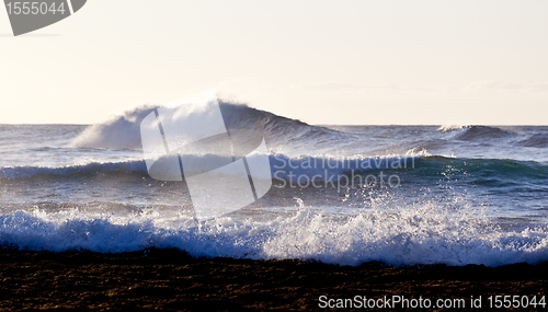 Image of Setting sun lights crashing waves