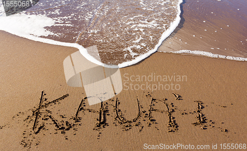 Image of Kauai written in sand with waves