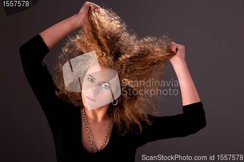 Image of Beautiful woman  with hands holding the hair, looking to camera, studio shot