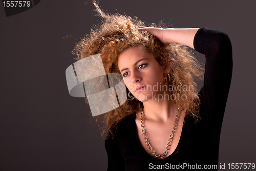 Image of Beautiful woman  with hands holding the hair, looking to camera, studio shot