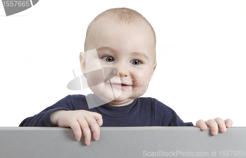 Image of young child standing behind grey cardboard