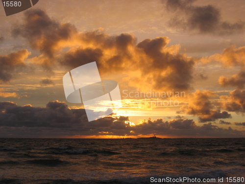 Image of A sunset over the sea with a lighthouse in the horizon