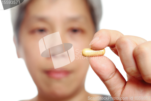 Image of mature woman holding pill