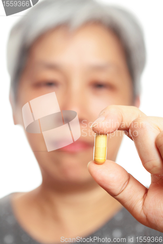 Image of mature woman holding pill