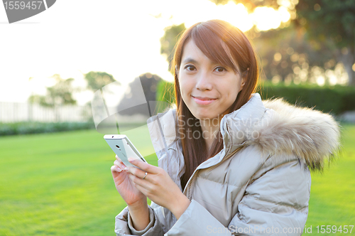 Image of young woman with phone outdoors