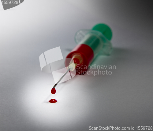 Image of syringe laying on table filled with blood