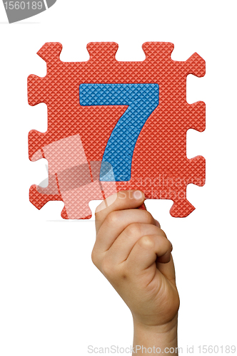 Image of Children hand holding the number Seven. White isolated number
