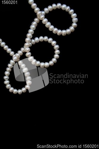 Image of White pearls on the black silk as background 