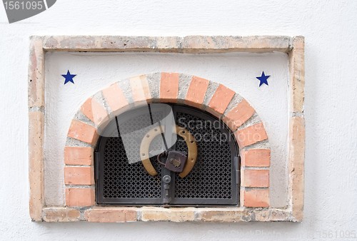 Image of Small ventilation window with grate, padlock and horseshoe