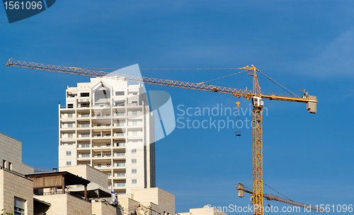 Image of Lifting crane and apartment building under construction