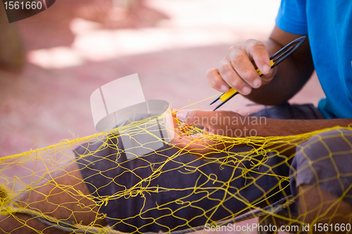 Image of Fisherman repairing fishing net