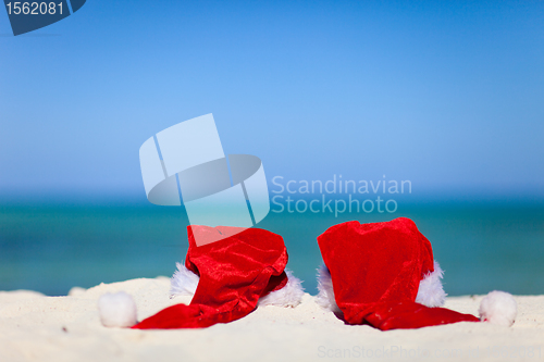 Image of Two red Santa hats on beach