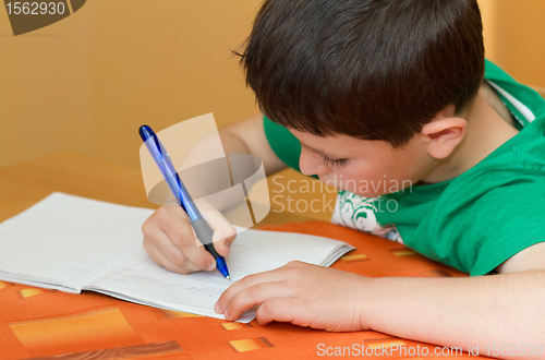 Image of boy writting homework from school in workbook