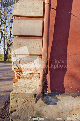 Image of crumbling brick house corner wall rainwater pipe 