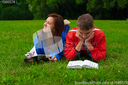 Image of two teenagers studying outdoors on grass