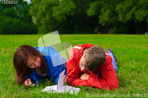 Image of two teenagers studying outdoors on grass