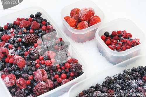 Image of Plastic containers of frozen mixed berries in snow