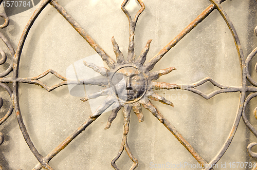 Image of Closeup of decorative metal gate. Sun in middle. 