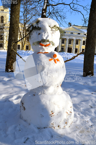 Image of Snow man decorated with orange bark spruce branch 