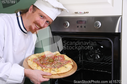 Image of young chef with italian pizza in kitchen