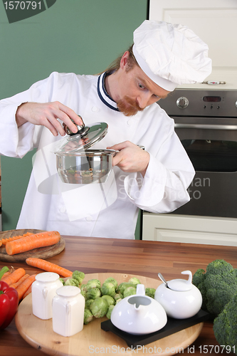 Image of Funny young chef strange looking at pot