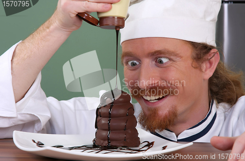 Image of Funny young chef added chocolate sauce at piece of cake
