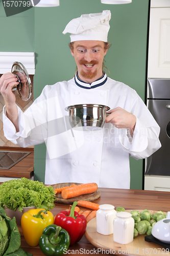 Image of Funny young chef strange looking at pot