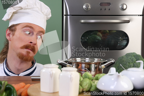 Image of Funny young chef strange looking at pot