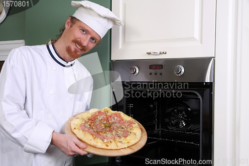 Image of young chef with italian pizza in kitchen