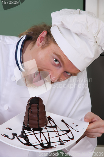 Image of Funny young chef eating a piece of cake