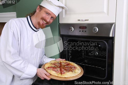 Image of young chef with italian pizza in kitchen