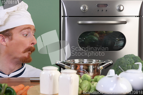 Image of Funny young chef strange looking at pot