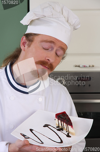 Image of Funny young chef smelling a piece of cake