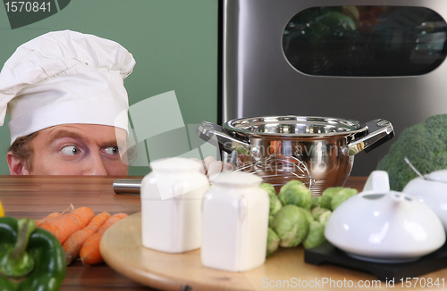 Image of Funny young chef strange looking at pot