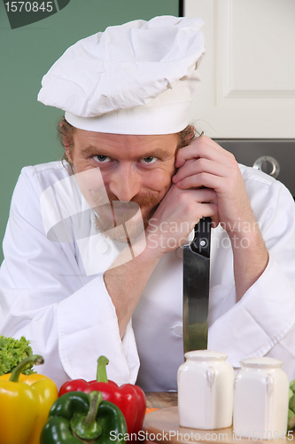 Image of Funny young chef with a knife in kitchen 