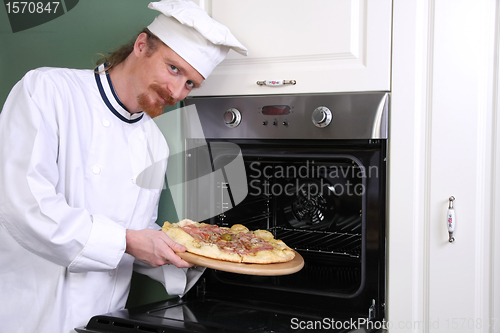Image of young chef with italian pizza in kitchen