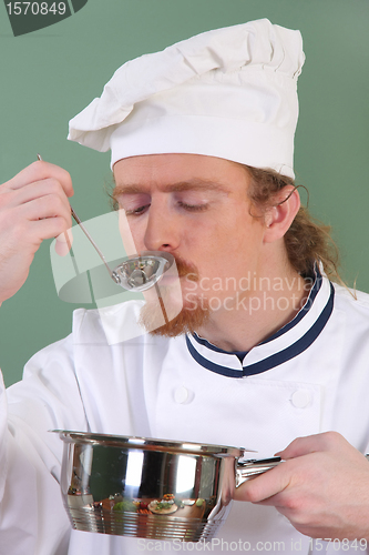 Image of young Chef tasting food with a tablespoon