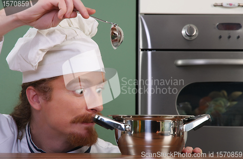 Image of Funny young chef strange looking at pot