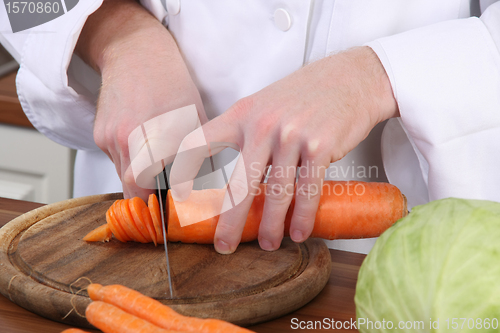 Image of chef preparing lunch and cutting carrot with knife