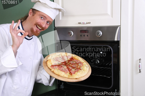Image of young chef with italian pizza in kitchen 