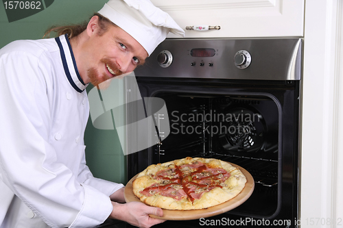 Image of young chef with italian pizza in kitchen